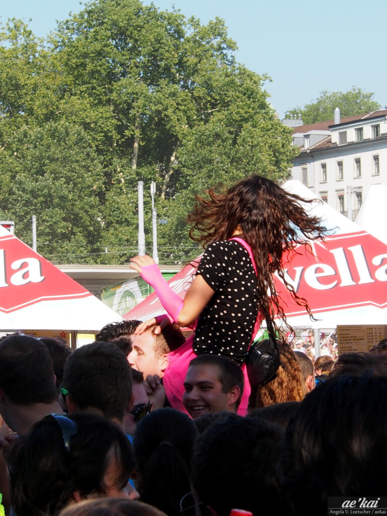 Streetparade, woman on shoulders and partying in a crowd